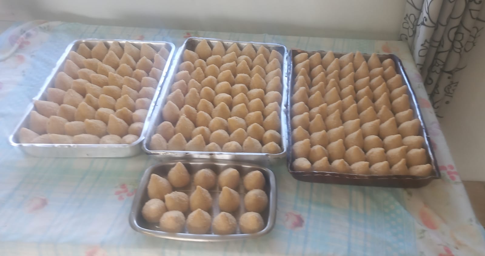 Bandejas com coxinhas e bolinhas empanadas prontas para fritar